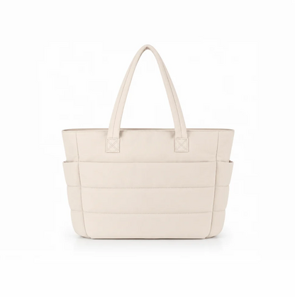 Shoulder bag in beige faux leather with padded horizontal stitching and dual top handles, featuring side pockets.