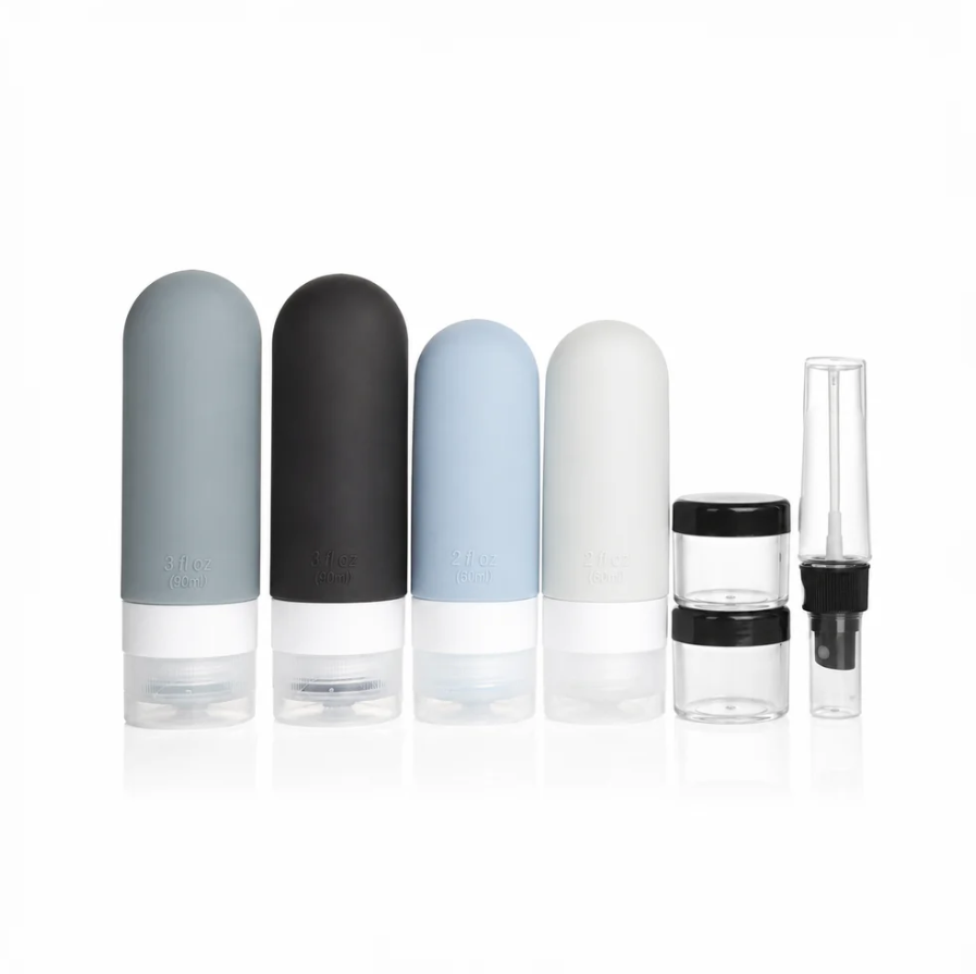 Travel bottle set with four silicone bottles in grey, black, blue, and white, two clear jars, and a spray bottle.